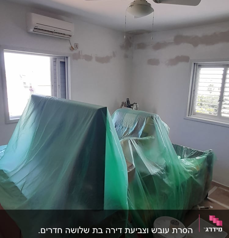 חדר עם רהיטים מכוסים בניילון, דלי צבע ומגש צביעה